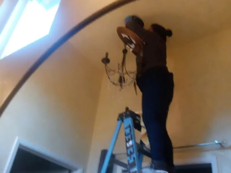 Electrician installing a chandelier in a Brandon residence